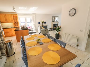 A dining area with a wooden table and yellow placemats next to a kitchen and living room at 12 Hillview in Ludden near Buncrana