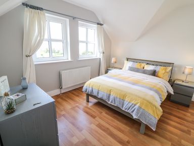 A bedroom with a bed with yellow and gray bedding and two bedside tables with lamps at 12 Hillview in Ludden near Buncrana