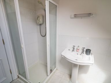 A bathroom with a shower cubicle and a pedestal sink with soap dispenser and toothbrush holder at 12 Hillview Ludden near Buncrana