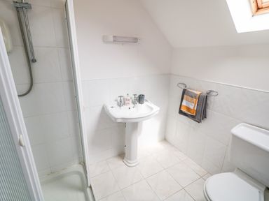 A bathroom with a shower, pedestal sink, towel rack with towels, and toilet at 12 Hillview Ludden near Buncrana