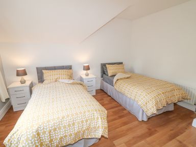 A bedroom with two single beds with yellow patterned bedding and nightstands with lamps at 12 Hillview in Ludden near Buncrana