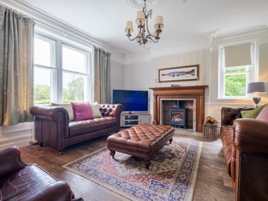 A living room with brown leather sofas a wooden fireplace and a television at Swinside Lodge in Newlands Valley near Keswick