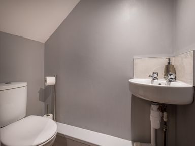 A small bathroom with a toilet and a corner sink with a soap dispenser at Swinside Lodge in Newlands Valley near Keswick