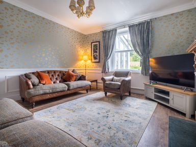 A living room with a sofa armchair television and lamp at Swinside Lodge in Newlands Valley near Keswick