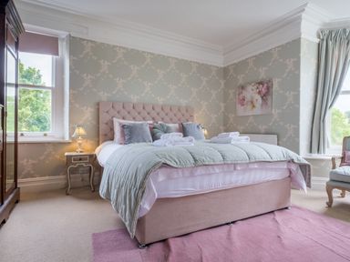A bedroom with a bed and side tables and large windows at Swinside Lodge in Newlands Valley near Keswick