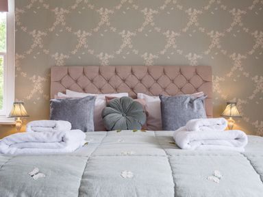 A bedroom with a bed with folded white towels and decorative pillows at Swinside Lodge in Newlands Valley near Keswick