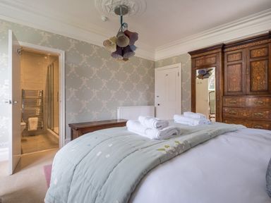 A bedroom with a bed with folded towels wooden furniture and an open door to a bathroom at Swinside Lodge in Newlands Valley near Keswick