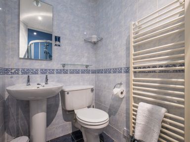 A bathroom with a sink mirror toilet towel rack and shower at Swinside Lodge in Newlands Valley near Keswick