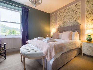 A bedroom with a large bed with folded towels bedside tables and lamps at Swinside Lodge in Newlands Valley near Keswick
