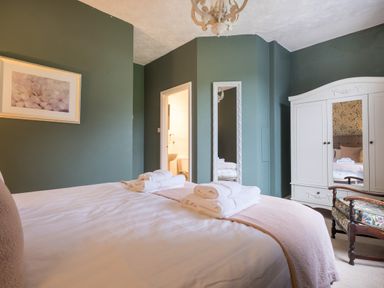 A bedroom with a bed and folded towels a white wardrobe and a chair with floral upholstery at Swinside Lodge in Newlands Valley near Keswick