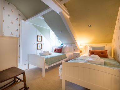 A bedroom with two single beds and a small bedside table with a lamp at Swinside Lodge in Newlands Valley near Keswick