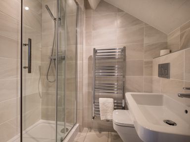 A bathroom with a glass-enclosed shower a towel rack a toilet and a rectangular sink at Swinside Lodge in Newlands Valley near Keswick