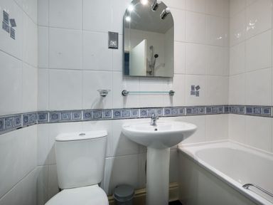 A bathroom with a toilet sink bathtub mirror and tiled walls at Swinside Lodge in Newlands Valley near Keswick