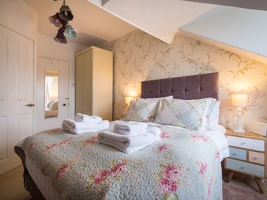 A bedroom with a double bed with folded towels bedside tables lamps and a wardrobe at Swinside Lodge in Newlands Valley near Keswick