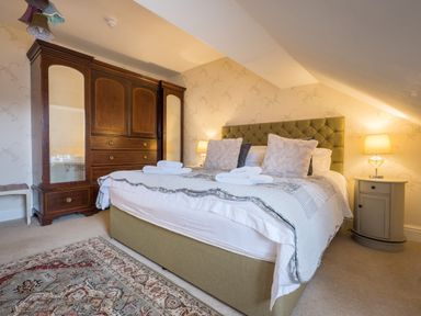 A bedroom with a bed with folded towels a wooden wardrobe bedside tables and lamps at Swinside Lodge in Newlands Valley near Keswick