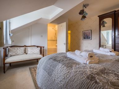 A bedroom with a bed with folded towels an armchair a wardrobe and an open door leading to a bathroom at Swinside Lodge in Newlands Valley near Keswick