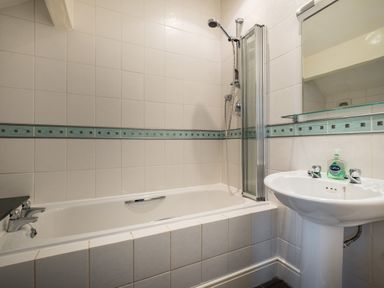 A bathroom with a bathtub shower combination and a pedestal sink at Swinside Lodge in Newlands Valley near Keswick