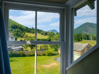 A view through a window showing a green garden and hills at Swinside Lodge Newlands Valley near Keswick