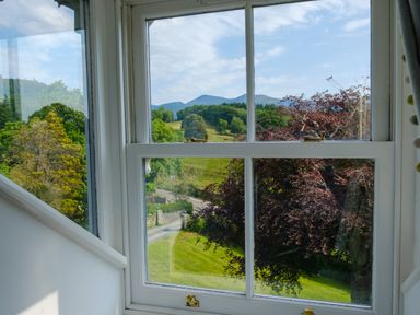 A window with a view of trees grassy fields and hills at Swinside Lodge in Newlands Valley near Keswick