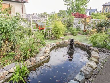 A garden with a pond surrounded by rocks and plants at Haddef Penmaenmawr in Penmaenmawr