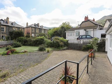 A driveway with potted plants and a gravel area next to houses at Haddef Penmaenmawr in Penmaenmawr