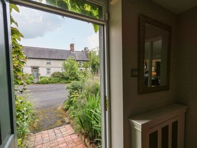 View through an open door showing a paved path with plants on the side and a house across the road at Scarvagh House in Scarva near Loughbrickland