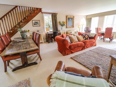 A living room with a wooden dining table and chairs a red sofa and a staircase at Scarvagh House Scarva near Loughbrickland