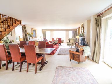 A large room with dining table and chairs a sitting area with sofas and armchairs and large windows at Scarvagh House in Scarva near Loughbrickland