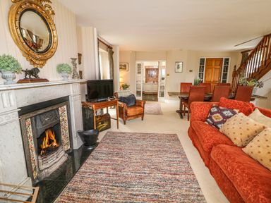 A living room with a fireplace a red sofa an armchair a TV and a dining table at Scarvagh House Scarva near Loughbrickland