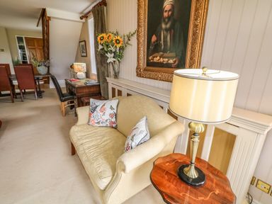 A room with a beige sofa with pillows a table lamp on a wooden side table a painting on the wall and a desk with chairs and flowers Scarvagh House Scarva near Loughbrickland