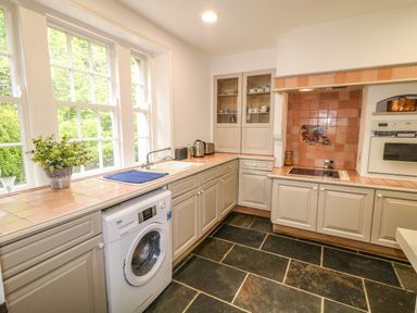 A kitchen with tiled countertops a washing machine a sink a stove and cabinets at Scarvagh House in Scarva near Loughbrickland