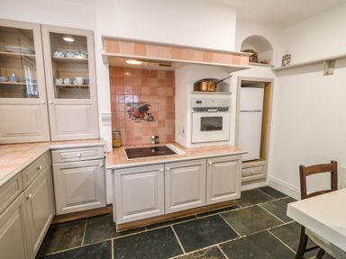 A kitchen with cabinets a stove an oven a refrigerator and a chair at Scarvagh House Scarva near Loughbrickland