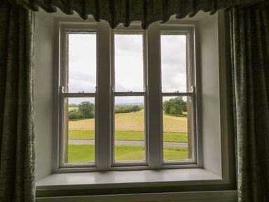 A window with three panes showing a view of fields and trees at Scarvagh House in Scarva near Loughbrickland