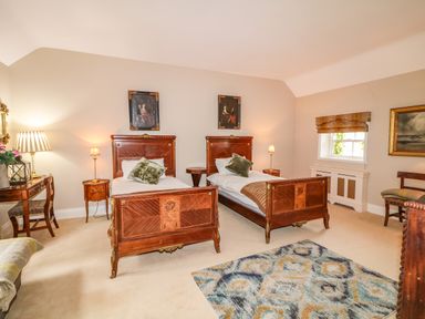 A bedroom with two wooden beds side by side and framed paintings above them at Scarvagh House Scarva near Loughbrickland