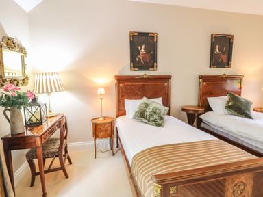 A bedroom with two single beds a wooden desk with a chair and lamps at Scarvagh House Scarva near Loughbrickland