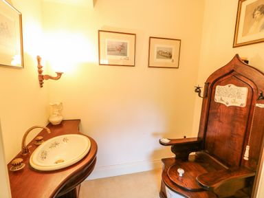 A room with a wooden washbasin with floral sink and a wooden chair with armrests and candle holders at Scarvagh House Scarva near Loughbrickland