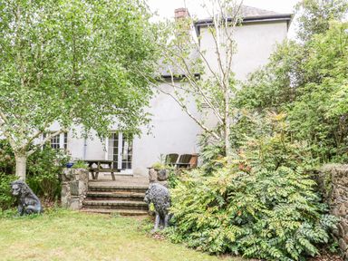A garden with stone steps leading to a patio with wooden table and chairs at Scarvagh House Scarva near Loughbrickland