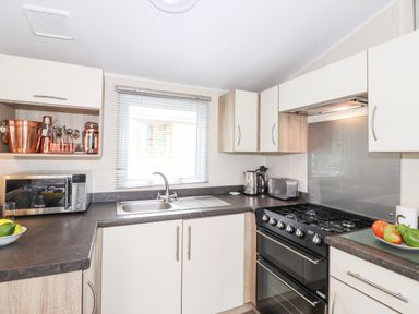 A kitchen with a sink a stove microwave toaster kettle and cabinets at Herdwick Cabin Troutbeck 68 White Cross Bay Holiday Park near Windermere