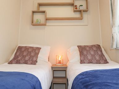 A bedroom with two single beds blue blankets and patterned pillows at Herdwick Cabin in Troutbeck 68 White Cross Bay Holiday Park near Windermere