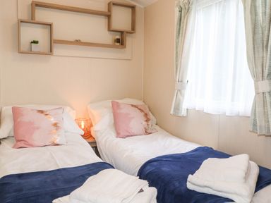 A bedroom with two single beds pink pillows and blue blankets at Herdwick Cabin in Troutbeck 68 White Cross Bay Holiday Park near Windermere