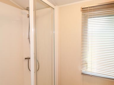 A bathroom with a shower and a window with blinds at Herdwick Cabin Troutbeck 68 White Cross Bay Holiday Park near Windermere
