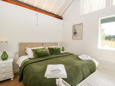 A bedroom with a bed covered in green bedding and white towels on it at The Old Kennels in Harcombe near Sidford