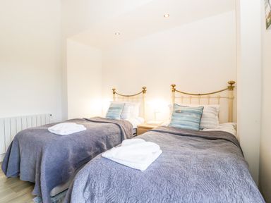 A bedroom with two single beds with blue quilts and pillows at The Old Kennels in Harcombe near Sidford