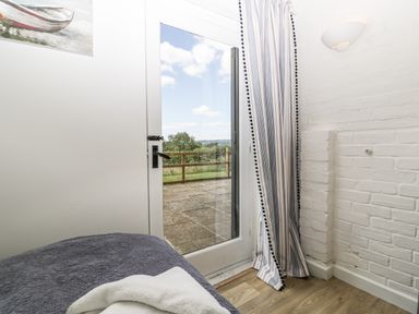 A bedroom with a bed near a glass door leading to a patio at The Old Kennels Harcombe near Sidford