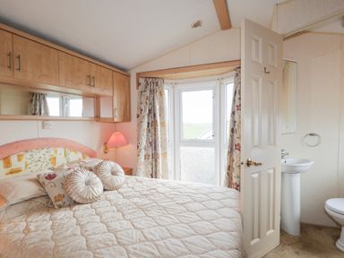 A bedroom with a bed pillows wall cabinets window and an open door leading to a bathroom at The Cabin in Occumster near Lybster