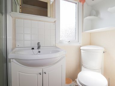 A bathroom with a sink and cabinet a window and a toilet at The Cabin in Occumster near Lybster