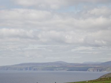 A coastal landscape with cliffs hills and the ocean at The Cabin in Occumster near Lybster