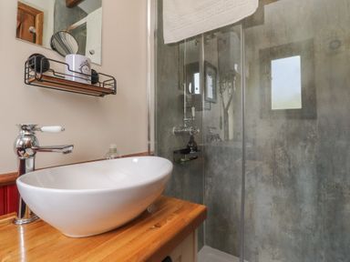 A bathroom with a wash basin and shower at The Journeyman Luxury Shepherds Hut in Barnoldswick