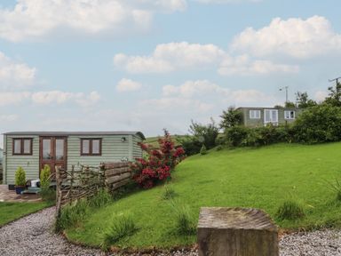 An outdoor area with a shepherd's hut and grassy landscape at The Journeyman Luxury Shepherds Hut Barnoldswick