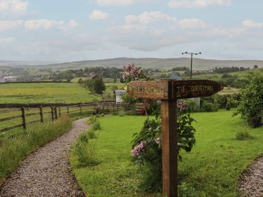 A garden with a signpost and gravel path at The Journeyman Luxury Shepherds Hut in Barnoldswick